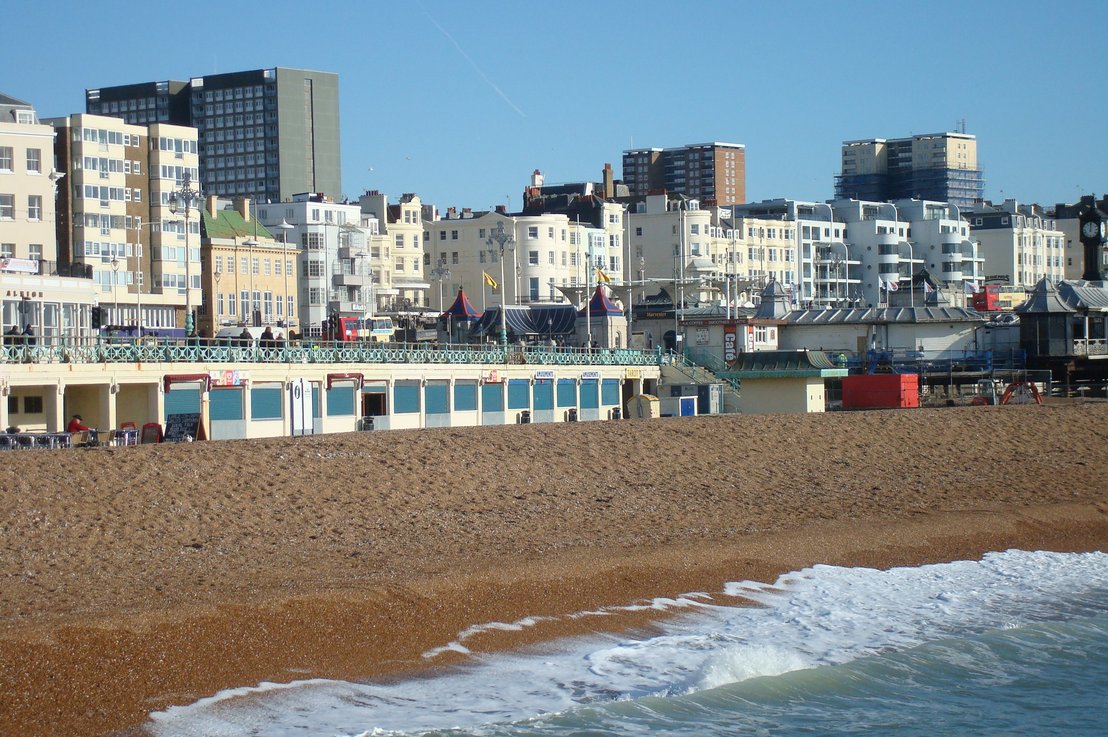 Widok na kamienistą plażę w Brighton z charakterystyczną nadmorską zabudową w tle, tworzącą klasyczny krajobraz brytyjskiego kurortu