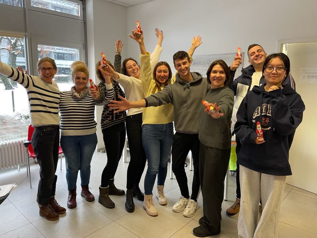 Group of students celebrating indoors, smiling and holding small chocolate Santas.
