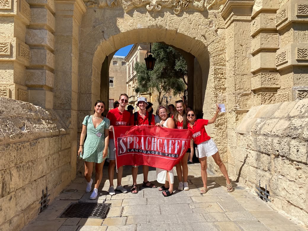 Students with Sprachcaffe flag at Mdina Gate, Malta.