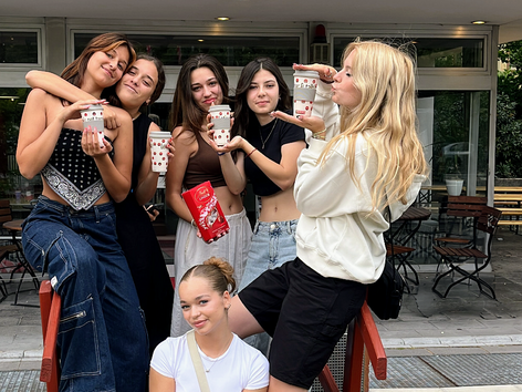 Group of female students posing with drinks outside a Sprachcaffe language school.