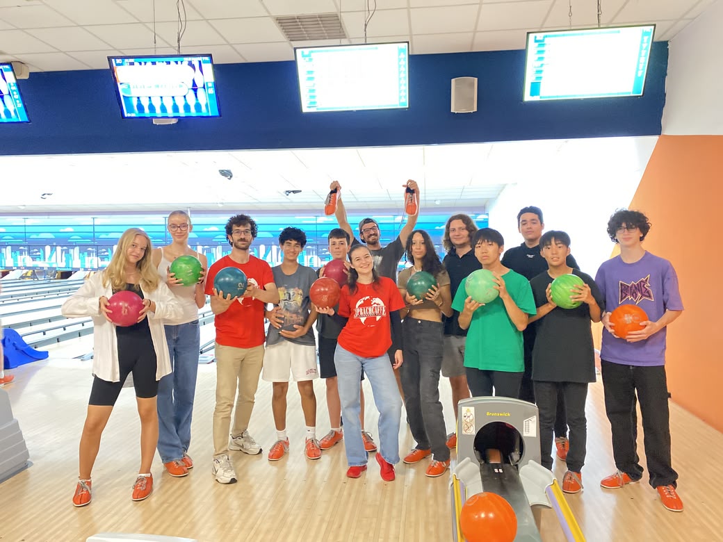 Sprachcaffe students posing with bowling balls during a fun indoor activity.