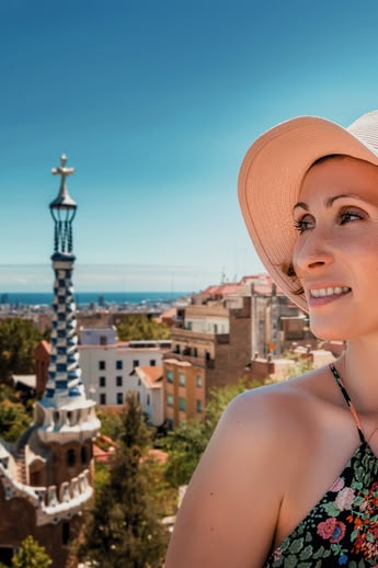 Smiling couple enjoying the view from Park Güell in Barcelona, Spain, with the city and sea in the background.