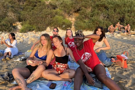 Grupa studentów relaksująca się na plaży, ciesząca się wspólnym czasem podczas słonecznego popołudnia na Malcie
