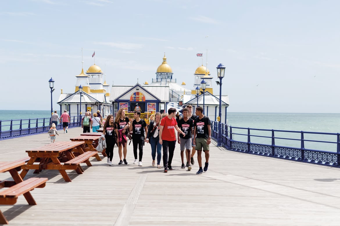 Sprachcaffe students walking along Eastbourne pier by the sea.