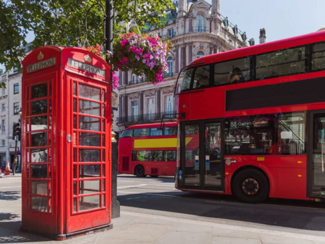 Classic red London telephone box and double-decker buses on a city street.