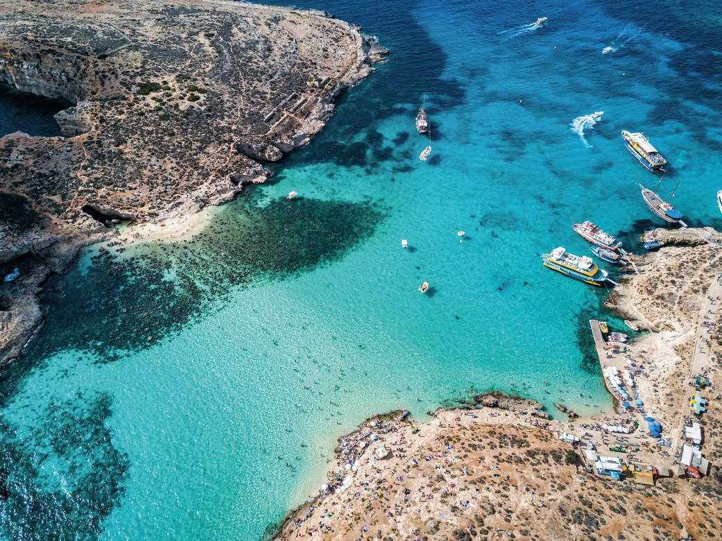 Aerial view of Comino’s Blue Lagoon with boats and tourists.
