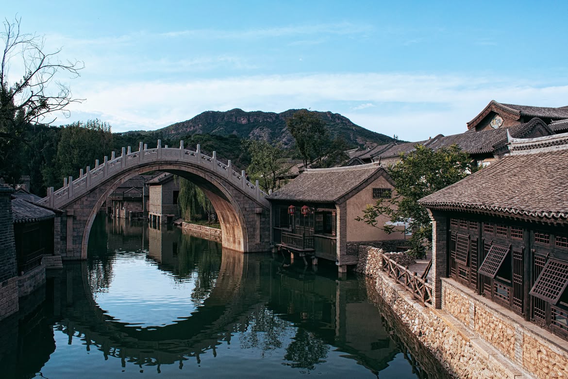 Traditional arched stone bridge reflecting in the canal of Wuzhen Water Town, China.