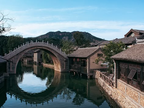 Traditional arched stone bridge reflecting in the canal of Wuzhen Water Town, China.