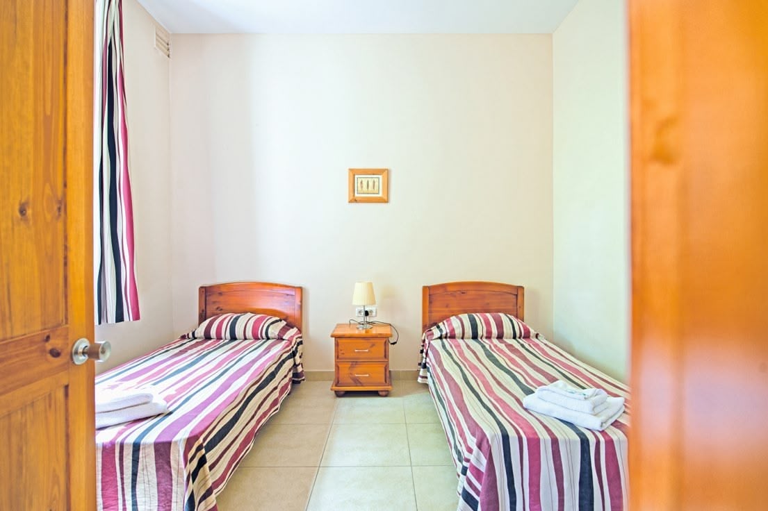 Pokój w standardowym apartamencie na kampusie Sprachcaffe na Malcie, wyposażony w dwa pojedyncze łóżka, stolik nocny i jasne, przytulne wnętrze, idealne do wypoczynku