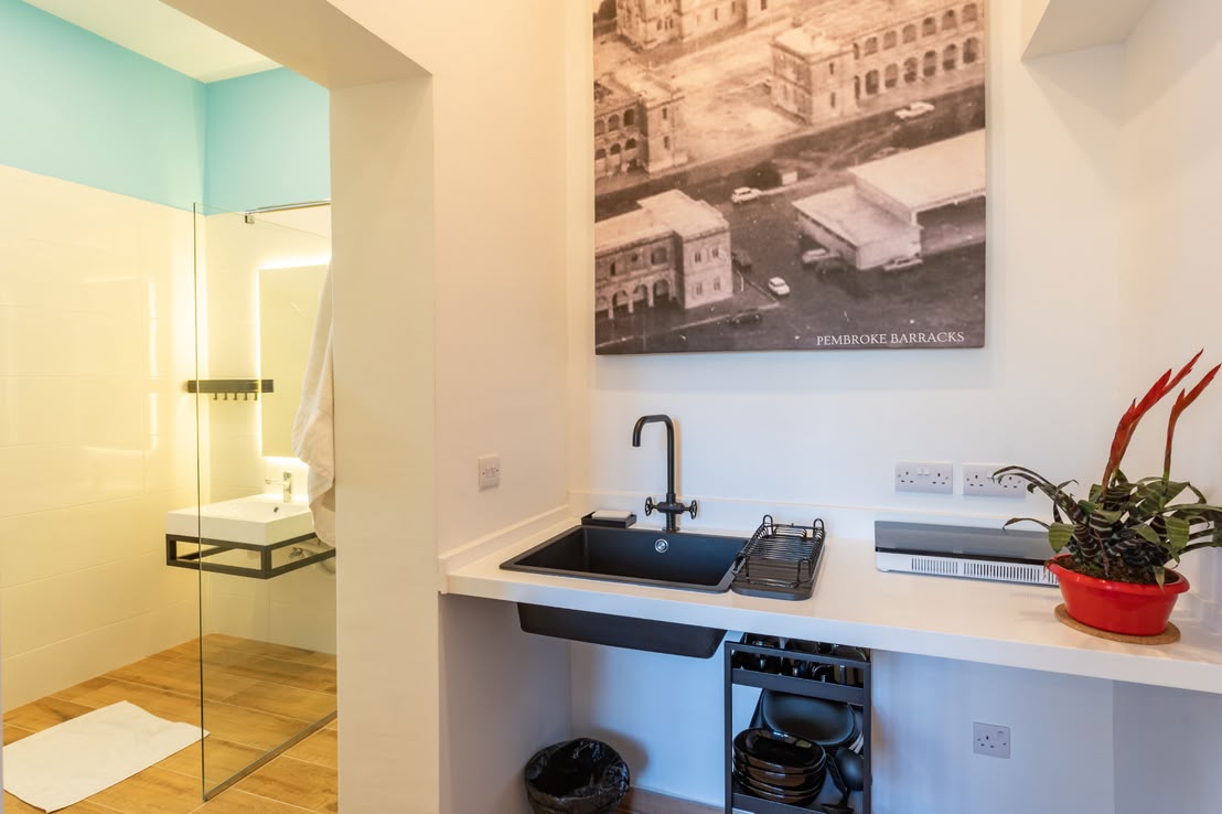Nowoczesne studio z aneksem kuchennym i łazienką, wyposażone w prysznic typu walk-in, oferujące komfortowe zakwaterowanie w eleganckim stylu
