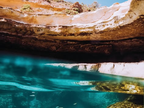 Teen jumping into a natural pool from a rocky cliff.
