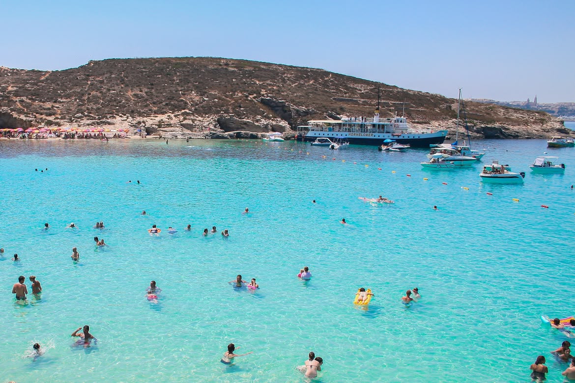 People swimming in the Blue Lagoon’s clear turquoise water.