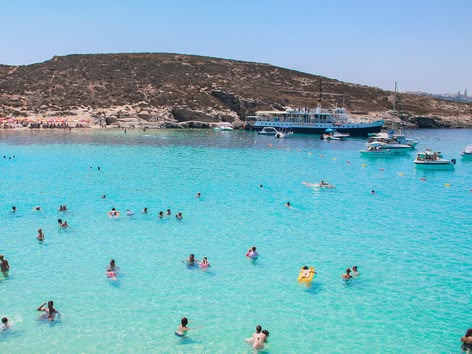 People swimming in the Blue Lagoon’s clear turquoise water.