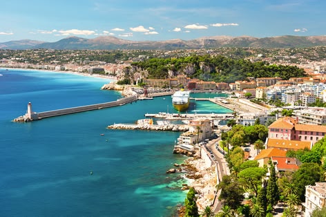 **ALT:** Widok z lotu ptaka na malowniczą Niceę, Francja, z turkusowymi wodami Morza Śródziemnego, portem i zabudową miejską otoczoną zielenią.