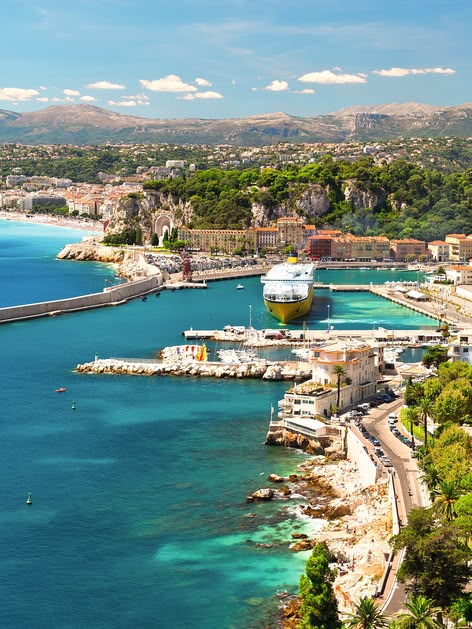 **ALT:** Widok z lotu ptaka na malowniczą Niceę, Francja, z turkusowymi wodami Morza Śródziemnego, portem i zabudową miejską otoczoną zielenią.