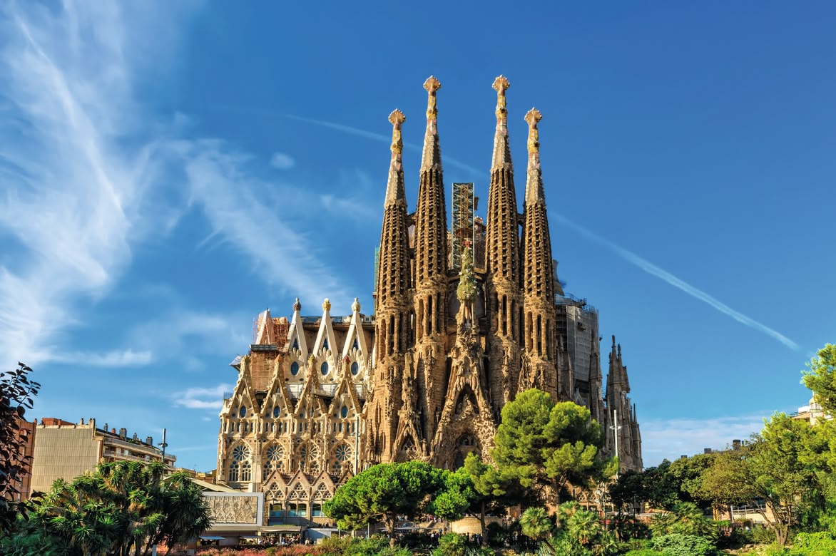 The Sagrada Família basilica in Barcelona under a clear blue sky.