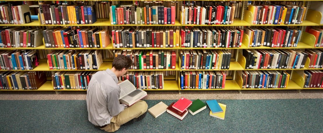 Książki w bibliotece, czytelnik czyta