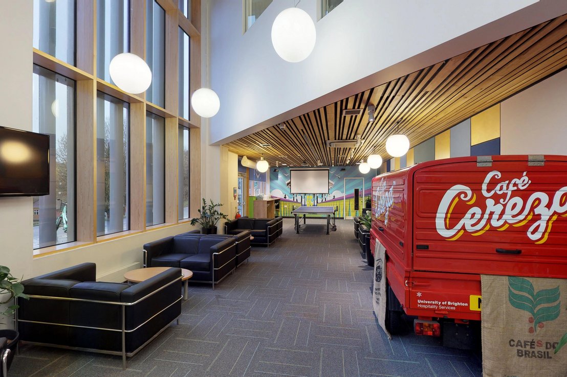 Stylowe lobby w rezydencji studenckiej w Brighton, wyposażone w wygodne sofy, designerskie oświetlenie i ciekawe elementy dekoracyjne, tworzące nowoczesną przestrzeń wspólną